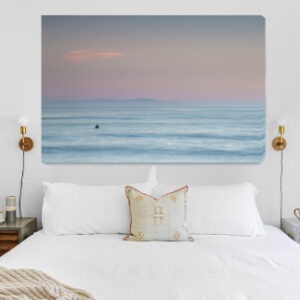 Peaceful cotton candy colouerd sky and ocean with one surfer hanging and waiting in the water