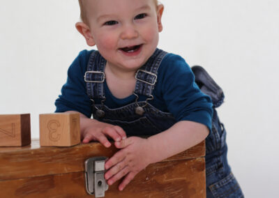 Baby with wooden box in studio and big smile