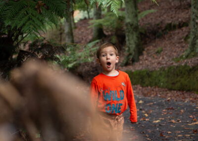 An expressive, surprised fun portrait of a young boy in an autumn forest, park. Outdoor children portrait photography in Auckland, New Zealand.