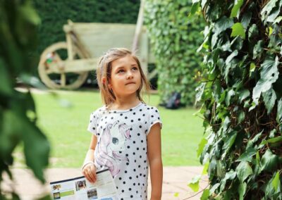 Curious young girl wondering in a garden with a map brochure. Outdoor portrait photography in Auckland, New Zealand.