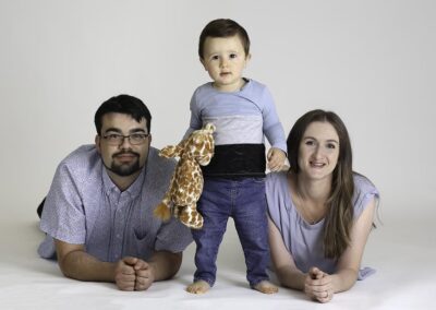 Happy family in portrait studio. Family photography in Auckland featuring mum, dad and toddler boy.