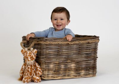 Happy toddler boy smiling in a basket, cute studio portrait photography in Auckland.