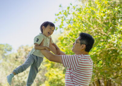 Young Asian child playing with dad. Happy summer family portrait in an Auckland Garden, New Zealand.