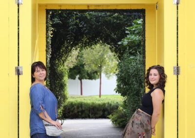 Family portrait of a Mum & Daughter in an architectural setting, with trees and park. Outdoor family portrait photography in Auckland, New Zealand.