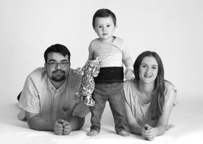 Happy family photo taken in a professional portrait studio. Family photography in Auckland featuring mum, dad and toddler boy.