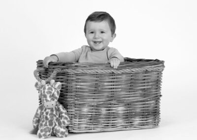 Happy toddler boy smiling in a basket, cute studio portrait photography in Auckland.