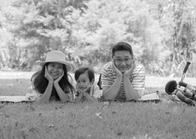 Professional Asian Family portrait with smiling mum, dad and young child. Happy, beautiful candid summer family portrait in an Auckland Garden, New Zealand.