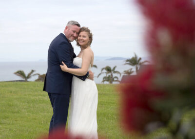 Smiling happy wedding photo with pohutukawa flowers