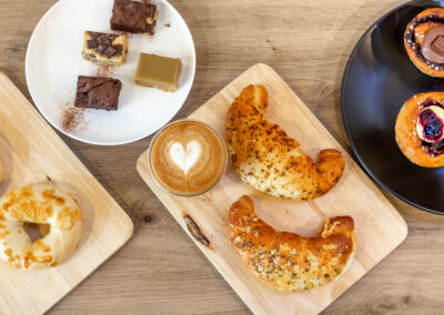 coffee with heart foam and cakes surrounded top view