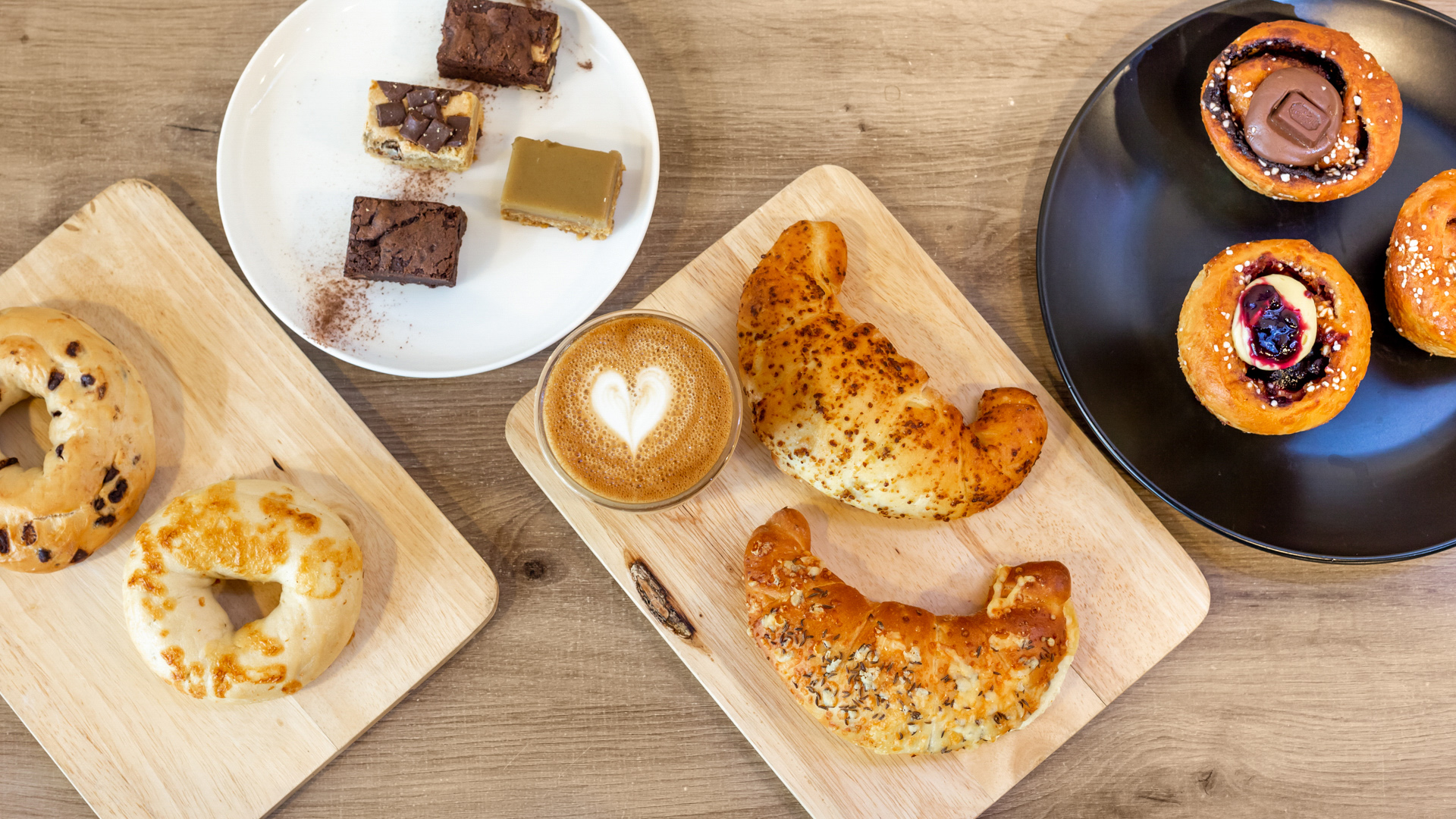 coffee with heart foam and cakes surrounded top view