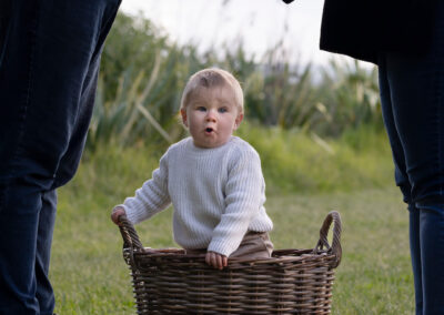 parents silhouette standing over baby in basket on grass