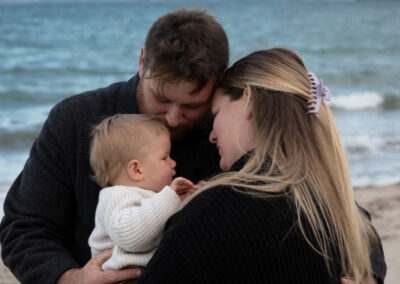 parents holding baby in tight on beach