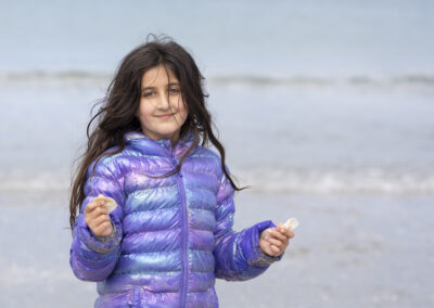 young girl on beach in purple shiny coat