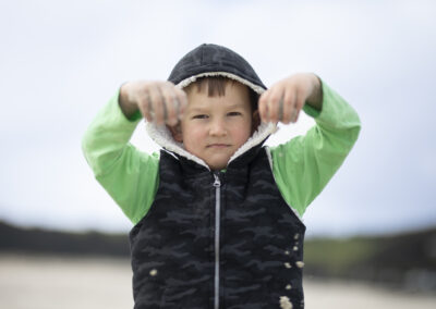 strict looking boy playing with sand on beach